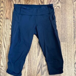 Black, cropped Lululemon leggings with pockets, ruched bottoms and zipped pocket